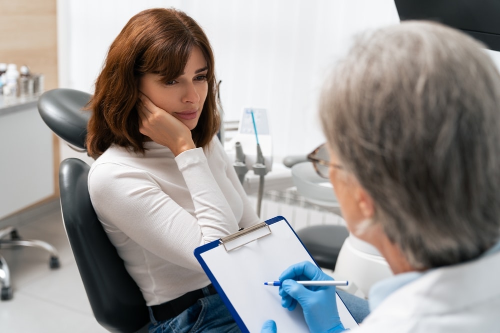 Patient holding their jaw in discomfort before an emergency dental visit